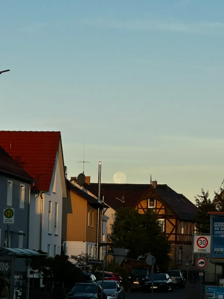 Full moon rising over the rooftops of a small-town street