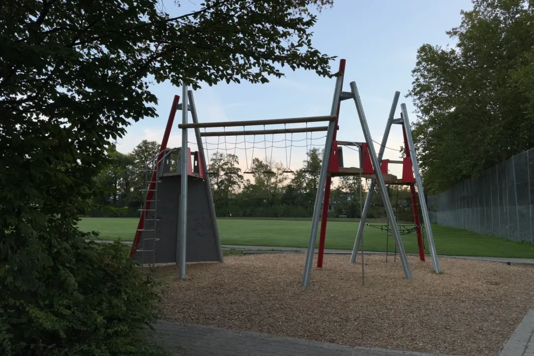 Playground at dusk with trees and a sports field