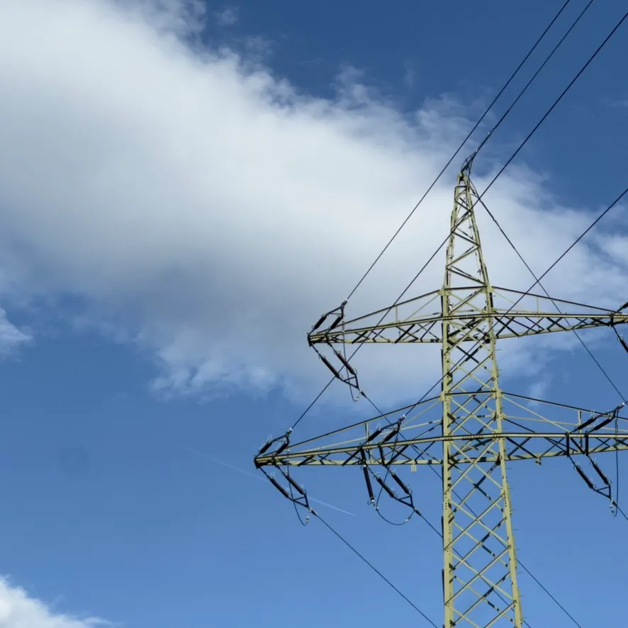Power pylon against a blue sky with clouds